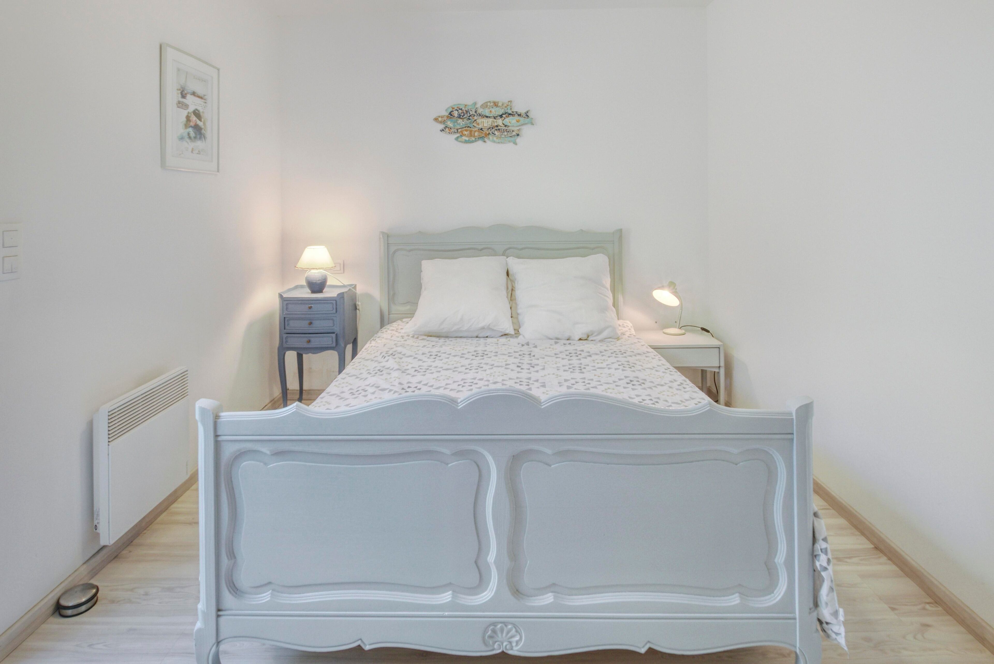 Ein Schlafzimmer mit einem weißen Bett, zwei Nachttischen und einer Heizung.