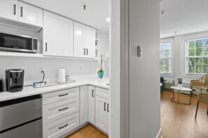 A modern kitchen with white cabinetry, a built-in microwave, and a coffee maker. - Condo/Pool/StepsToBeachDine/Island 1br (Palm Beach)