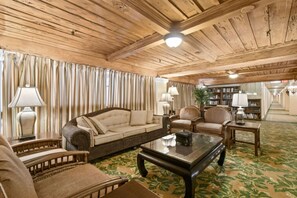 A room with a wooden ceiling, a sofa, armchairs, a coffee table, lamps, and a bookshelf. - Condo/Pool/StepsToBeachDine/Island 1br (Palm Beach)