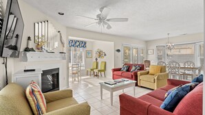 A spacious living room with a fireplace, a ceiling fan, and a dining area with a table and chairs. - Ruby Waves- Beach House with Private Pool, Short Walk to the Beach (North Myrtle Beach)