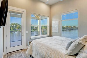 Una camera da letto con un letto grande, due finestre vista lago e una porta che dà all'esterno.