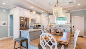 A spacious kitchen with white cabinetry, a central island, and a chandelier. - Paradise Found ~ Waterfront Pool Home, 50' Dock, Kayaks & Bikes (Marathon)