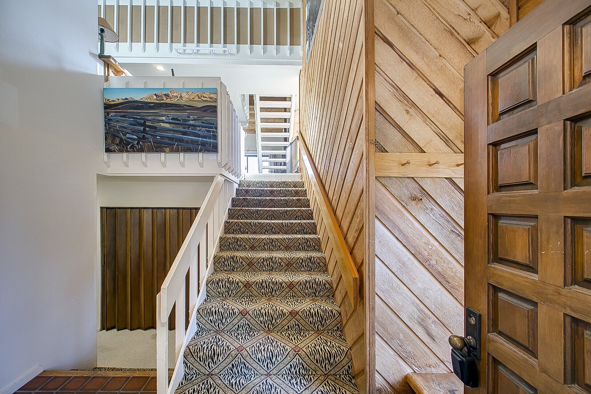 Una escalera con alfombra estampada que conduce a una puerta de madera.