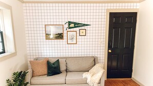 A living room with a grey sofa, a potted plant, a rug, and a door. - Steps to VT Campus & Cassell Cozy Blacksburg Studio (Blacksburg)
