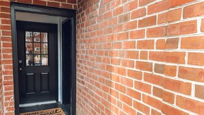 A brick wall with a black door and a doormat that reads "Home Sweet Home." - Steps to VT Campus & Cassell Cozy Blacksburg Studio (Blacksburg)