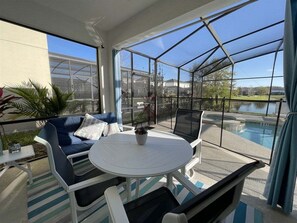 Une terrasse ensoleillée avec une table ronde, des chaises et un canapé.
