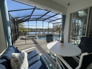 A covered outdoor seating area with a pool, a table, and chairs.