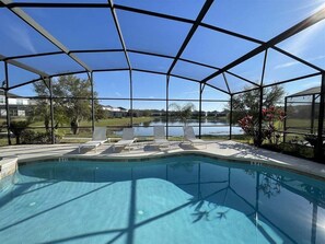 Une piscine dotée d’un espace couvert, de chaises longues et offrant une vue sur un lac.