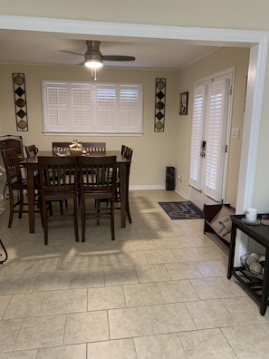 A dining area with a table and chairs, a ceiling fan, and a window with shutters.