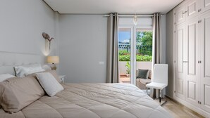 Une chambre avec un grand lit, une chaise, une table de chevet et une vue sur l’extérieur.