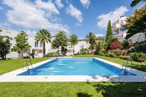 Una piscina con acqua cristallina e azzurra, circondata da erba curata e diversi alberi.