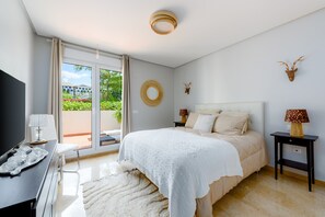 Une chambre à coucher avec un lit, une télévision, un bureau, une lampe et une vue sur la verdure.