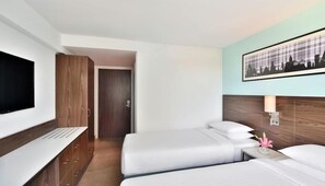 A hotel room with a TV, a desk, two beds, a nightstand, and a framed picture on the wall. - Fairfield by Marriott Bengaluru Whitefield (Bengaluru)
