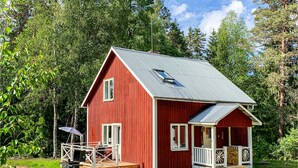 A red wooden cabin with a metal roof, a porch, and a deck. - 3 bedroom beautiful home in Ambjörby (Ambjörby)