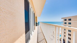 Een balkon met uitzicht op zee en omliggende gebouwen.
