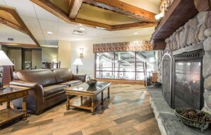 Relax in this inviting living area with a high ceiling, leather sofa, and stone fireplace.