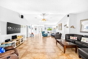 A spacious living area with a flat-screen TV, comfortable seating, and artwork on the walls. - Pool Home-Beachside-Hope's Haven (Port Orange)
