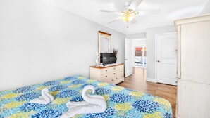 Um quarto com cama, penteadeira, espelho e ventilador de teto.