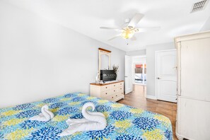 A bedroom with a bed, a dresser, a mirror, and a ceiling fan. - Pool Home-Beachside-Hope's Haven (Port Orange)