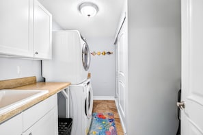 A narrow laundry room with a washing machine, a dryer, and a sink.