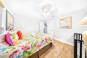 Un dormitorio con una cama, una puerta, un cuadro en la pared y una lámpara en el techo.