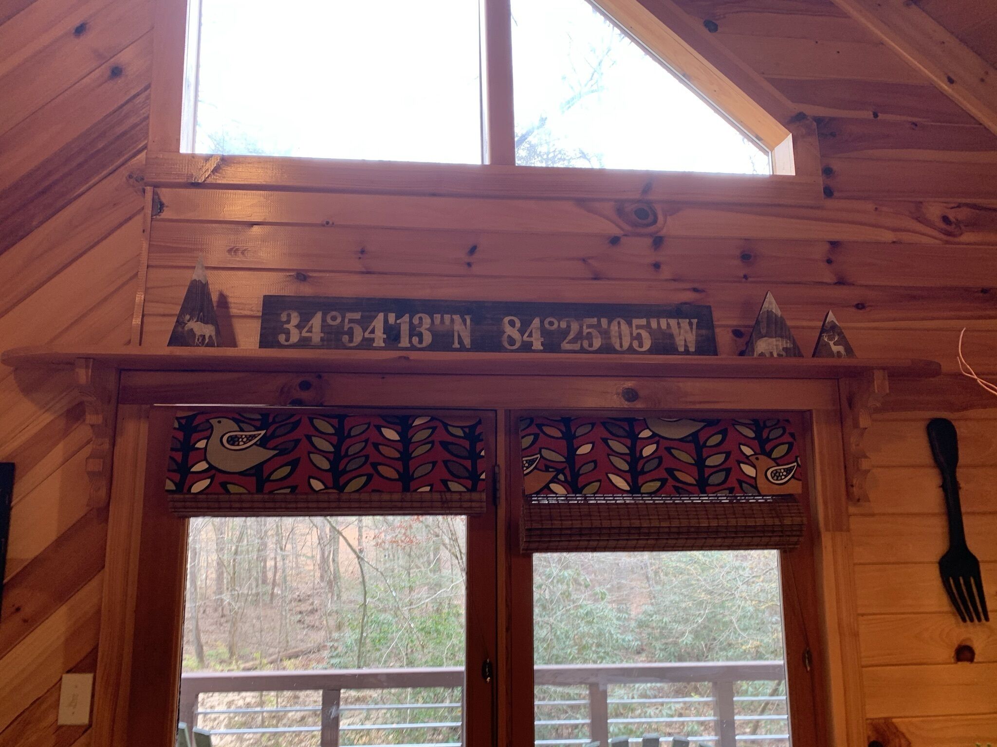 A wooden cabin interior with a wooden ceiling, a window, and a door with a decorative design.