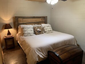 Une chambre à coucher avec une tête de lit en bois, une petite table de chevet avec une lampe et des coussins décoratifs.