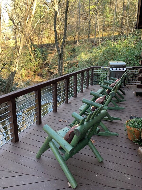 Une terrasse en bois avec des bancs verts et un barbecue.
