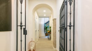 A hallway with a staircase, a table with plants, and a decorative item.