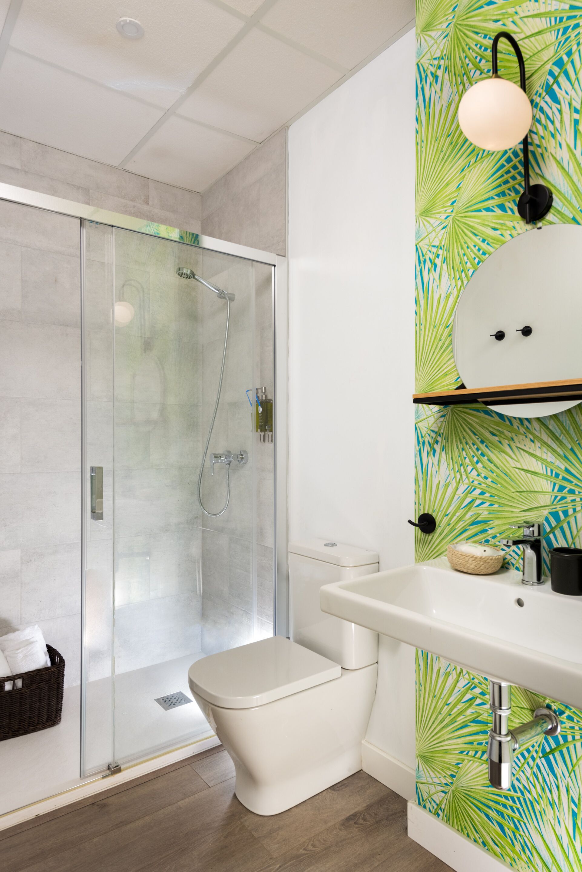 Un baño moderno con ducha envuelta en vidrio, inodoro blanco y lavamanos con un lavabo decorativo.