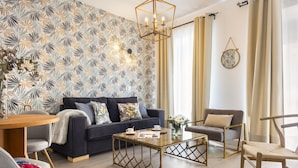 A modern living room with a dark blue sofa, a wooden coffee table, and a grey armchair.