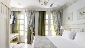 Una habitación de hotel con una cama, un televisor en la pared y cortinas.