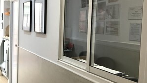 A hallway with a reception desk, framed pictures on the wall, and a bulletin board with notices. - LM Rooms Opera (Madrid)