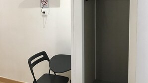 A room with a desk, chair, and a wardrobe with hanging clothes. - LM Rooms Opera (Madrid)