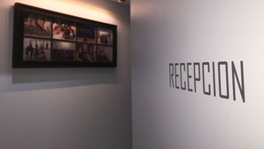 A reception area with a framed photo collage on the wall and the word "RECEPTION" in large letters. - LM Rooms Opera (Madrid)