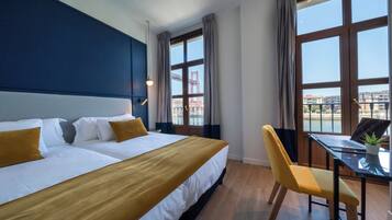 Una habitación de hotel con una cama grande, un escritorio con una computadora portátil y una silla.