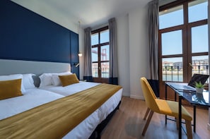 A hotel room with a large bed, a desk with a laptop, and a chair.