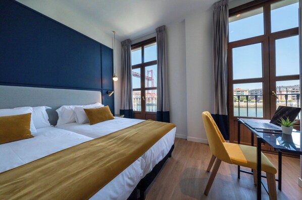 Una habitación de hotel con una cama grande, un escritorio con una computadora portátil y una silla.