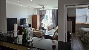 A room with a bed, a TV, a wooden cabinet, and a window with blinds. - Exceptional Luxury Resort (Boynton Beach)