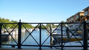 A marina with boats docked, a clear sky, and a building with balconies in the background. - Exceptional Luxury Resort (Boynton Beach)