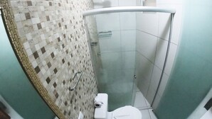 A small, compact bathroom with a tiled shower area, a toilet, and a sink. - Pousada Porto Maraca (Ipojuca)