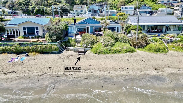 Une propriété située en bord de mer, avec une plage de sable, un escalier menant à une maison et une vue sur l’océan.