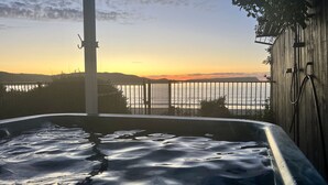 Un bain à remous avec vue sur la mer et les montagnes, au coucher du soleil.