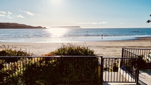 Une vue sur la plage avec une terrasse en bois et une rambarde en métal.