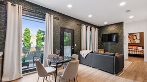 Un salon moderne avec un canapé, une table à manger et des chaises, et un téléviseur fixé au mur.