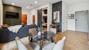 Un salon moderne avec un canapé, une table à manger et un téléviseur fixé au mur.