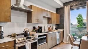 Une cuisine moderne avec des meubles en bois, des appareils électroménagers en acier inoxydable et une grande fenêtre donnant sur l’extérieur.