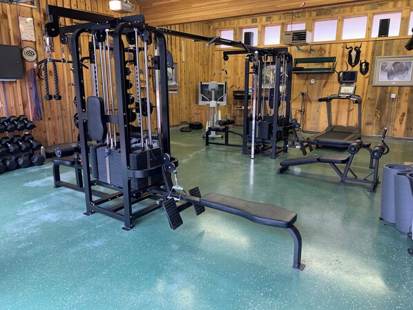 A gym with various exercise equipment, including a squat rack, benches, and dumbbells. - Mountain View Villa - Alpine Falls Ranch (Superior)