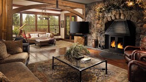 A spacious living room with a stone fireplace, leather furniture, and a large television.