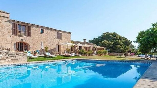 Un bâtiment en pierre doté d’une piscine, de chaises longues et d’un jardin bien entretenu.
